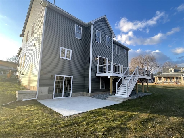 rear view of property with a deck, stairway, a lawn, and a patio area