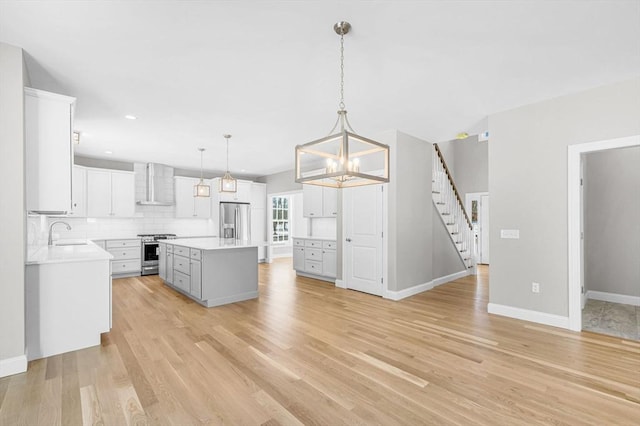 kitchen featuring stainless steel appliances, light countertops, light wood-type flooring, backsplash, and wall chimney exhaust hood