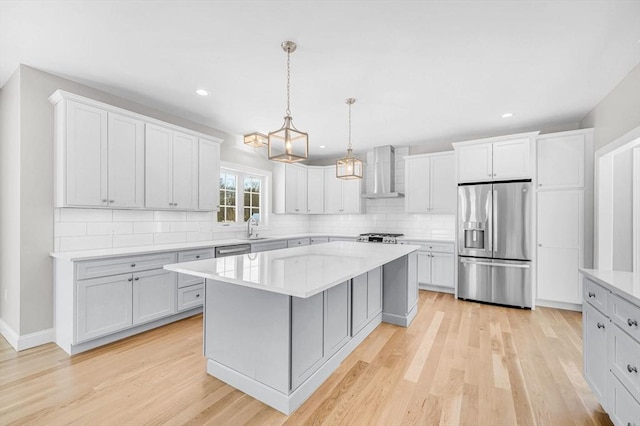 kitchen featuring wall chimney exhaust hood, stainless steel appliances, a sink, and light wood-style flooring