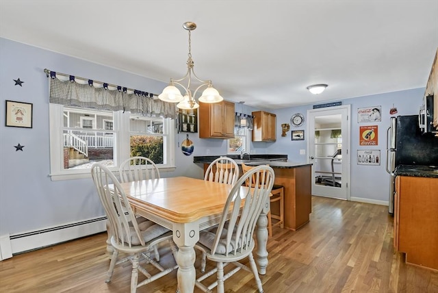 dining area with sink, light hardwood / wood-style flooring, baseboard heating, and an inviting chandelier