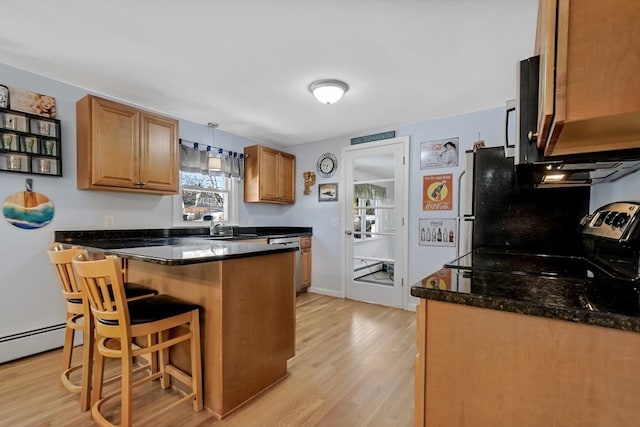 kitchen with a kitchen breakfast bar, sink, light hardwood / wood-style flooring, kitchen peninsula, and dark stone counters