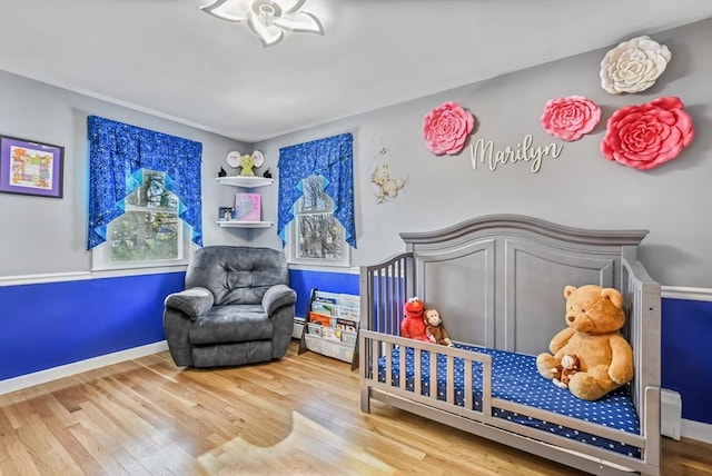 bedroom with a crib and hardwood / wood-style floors