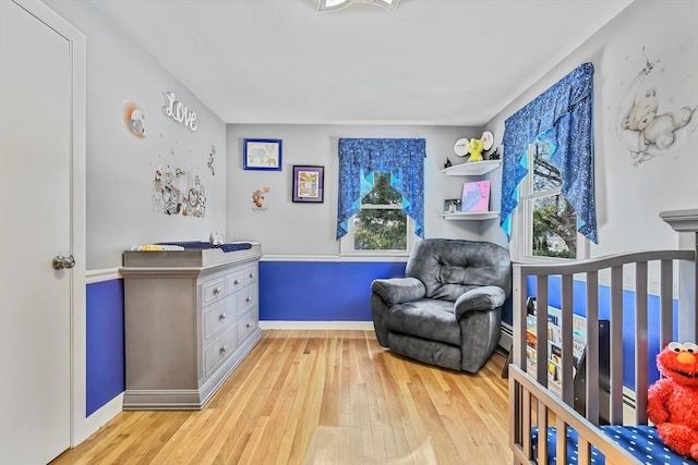 bedroom with light hardwood / wood-style floors and a crib