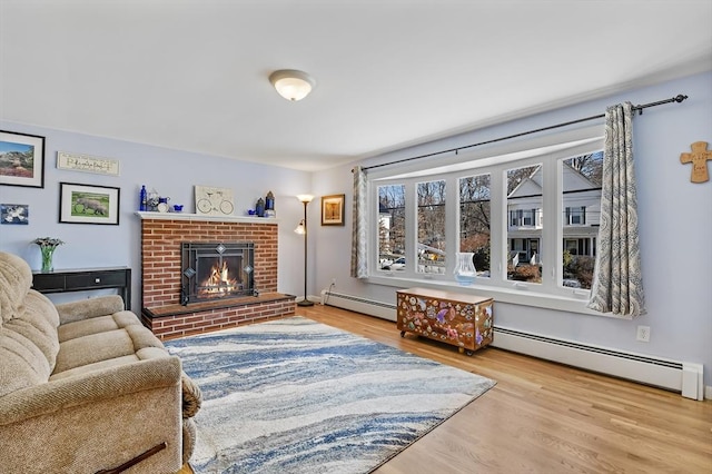 living room featuring a brick fireplace, light hardwood / wood-style floors, and a baseboard heating unit