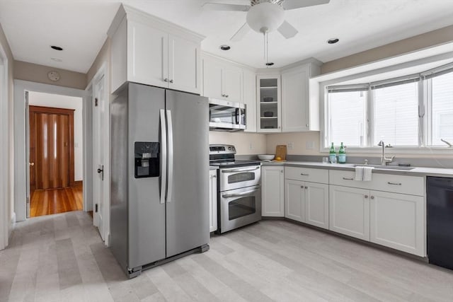 kitchen featuring stainless steel appliances, light countertops, white cabinets, and glass insert cabinets