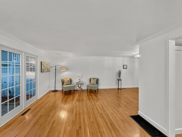 unfurnished room with baseboards, light wood-style flooring, visible vents, and crown molding