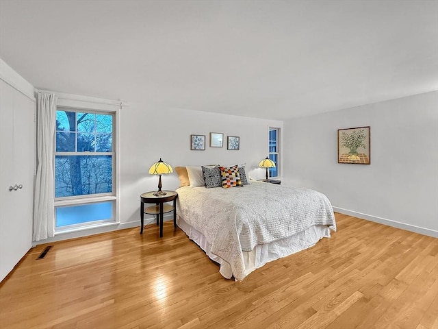 bedroom featuring light wood-style flooring, visible vents, and baseboards