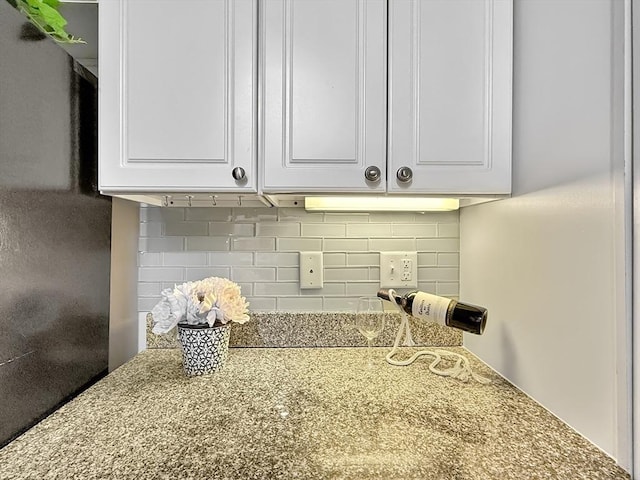 interior details featuring tasteful backsplash, stone countertops, and white cabinetry