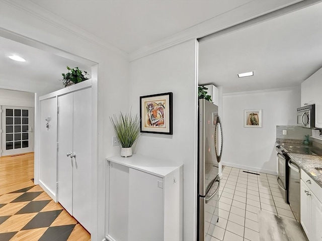 kitchen with baseboards, white cabinets, light countertops, ornamental molding, and appliances with stainless steel finishes