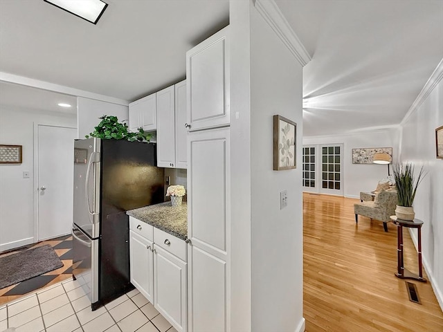 kitchen with crown molding, light wood finished floors, visible vents, freestanding refrigerator, and white cabinetry