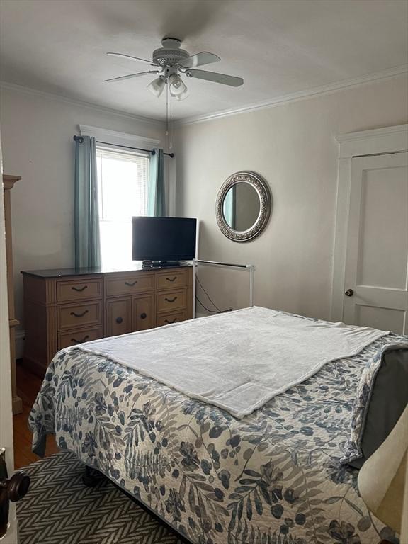 bedroom with ceiling fan, ornamental molding, and dark wood-style flooring