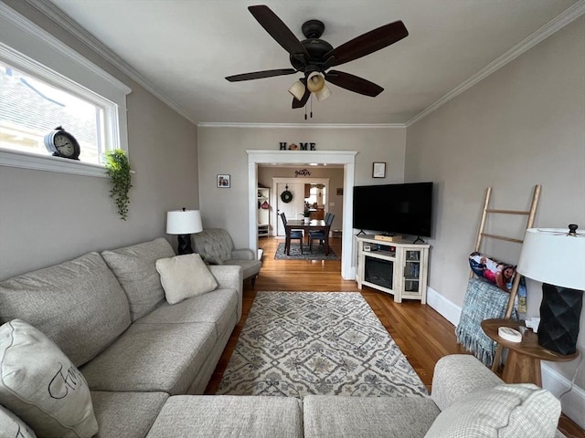 living area with crown molding, baseboards, ceiling fan, and wood finished floors