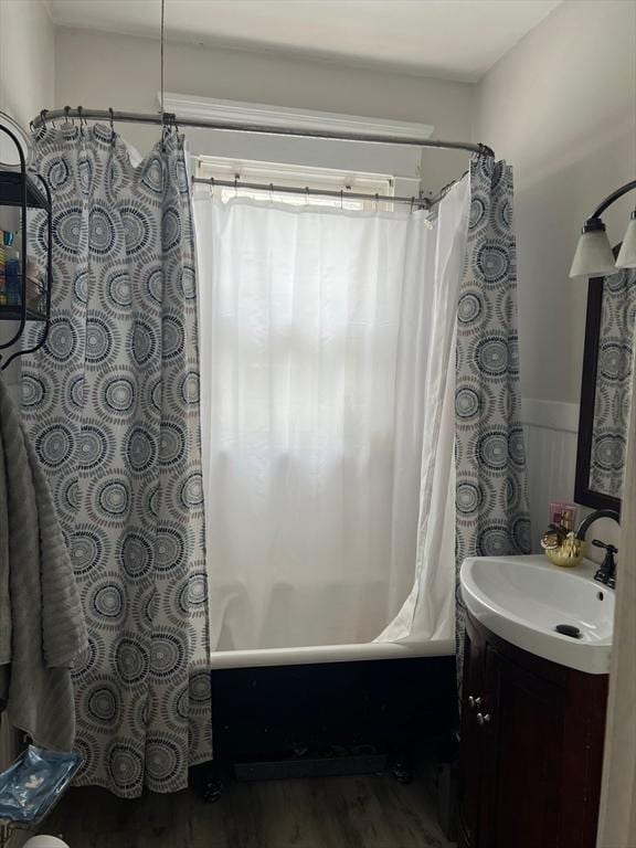 full bathroom featuring wainscoting, shower / bath combo with shower curtain, wood finished floors, and vanity