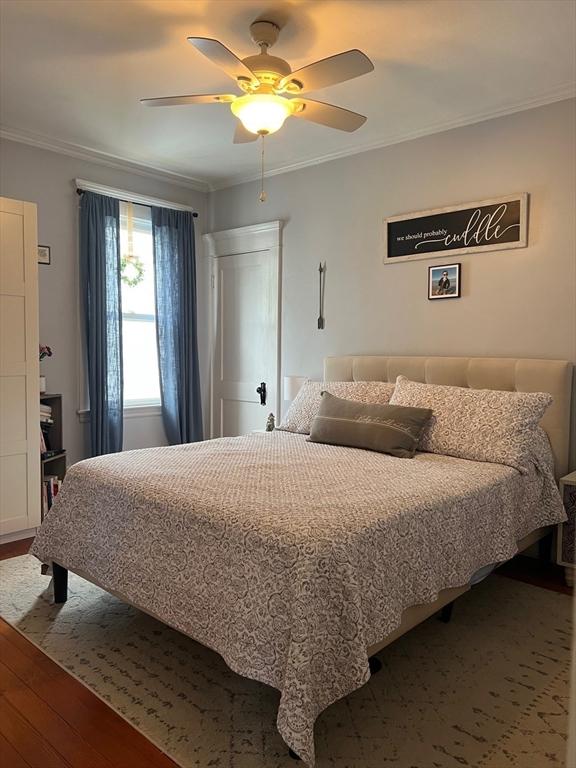 bedroom with a ceiling fan, crown molding, and hardwood / wood-style flooring