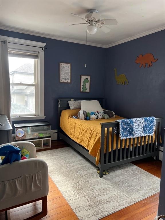 bedroom featuring crown molding, a ceiling fan, and wood finished floors