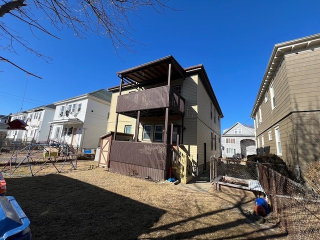 back of house featuring a balcony, a residential view, and fence