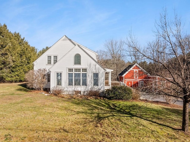 rear view of property featuring a lawn and an outbuilding