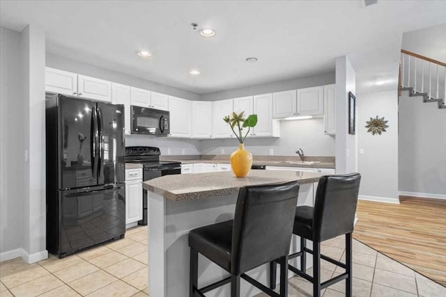 216 Reservoir St Unit 304, Holden, MA 01520 - kitchen featuring a sink, white cabinets, a breakfast bar area, light tile patterned floors, and black appliances