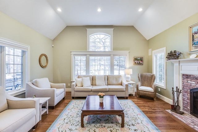 living room featuring a fireplace, baseboards, lofted ceiling, and wood finished floors