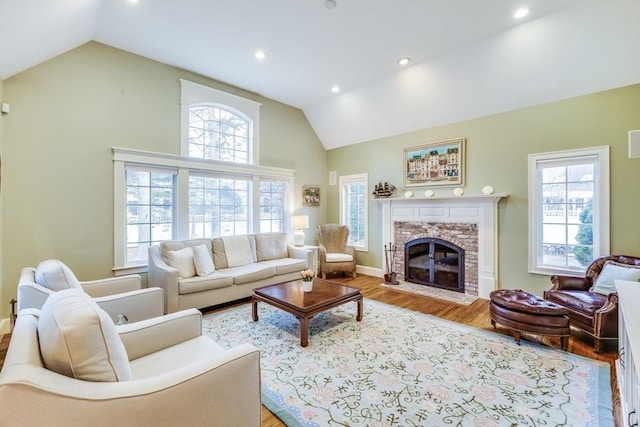 living area with a glass covered fireplace, recessed lighting, wood finished floors, and a wealth of natural light