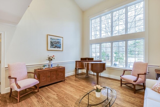 living area featuring baseboards, light wood finished floors, and high vaulted ceiling