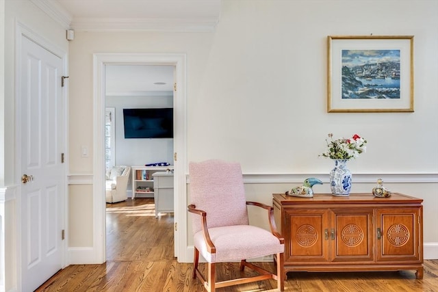 living area featuring light wood-style flooring, baseboards, and ornamental molding