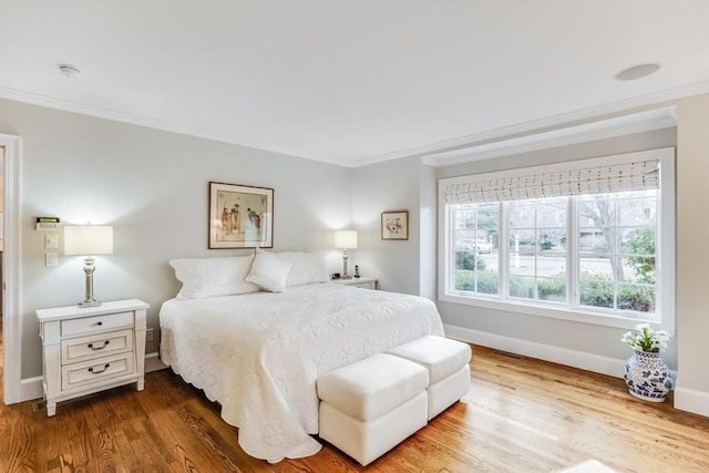 bedroom featuring baseboards, wood finished floors, and crown molding