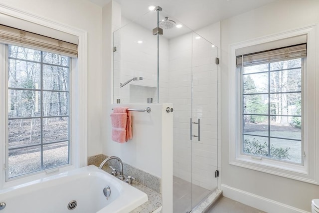 full bathroom with a tub with jets, plenty of natural light, and a stall shower