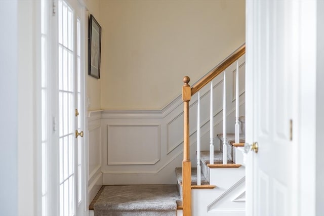 entryway with a wainscoted wall, stairs, and a decorative wall