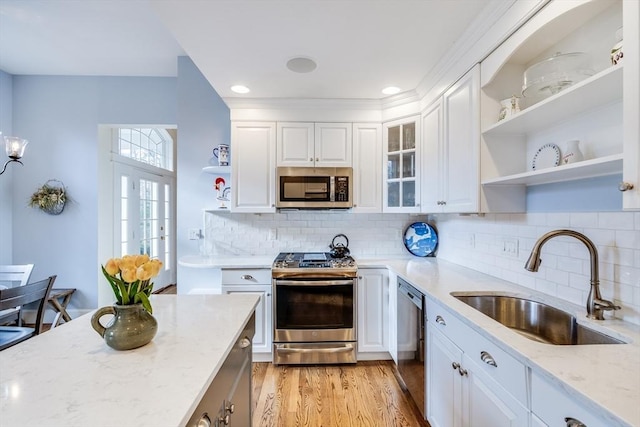 kitchen featuring open shelves, light stone countertops, stainless steel appliances, white cabinetry, and a sink