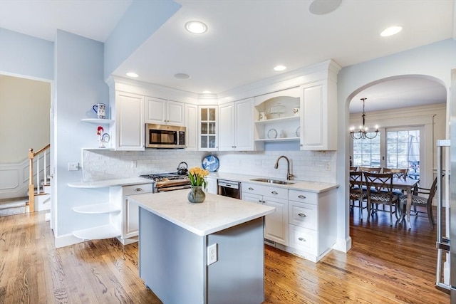 kitchen featuring open shelves, white cabinets, appliances with stainless steel finishes, and a sink