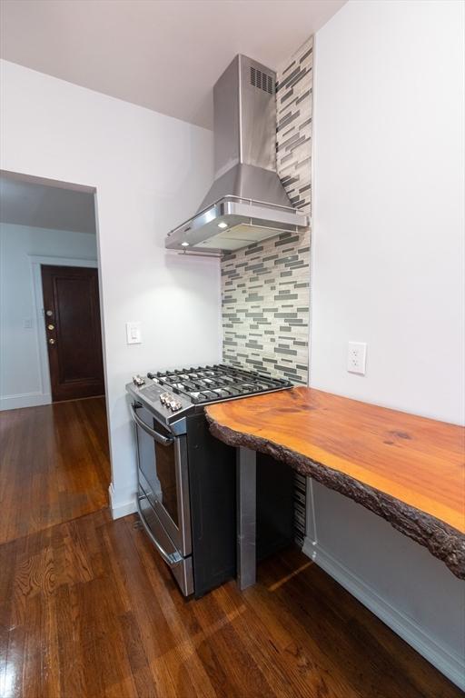 kitchen with tasteful backsplash, range hood, wood counters, gas stove, and dark hardwood / wood-style floors