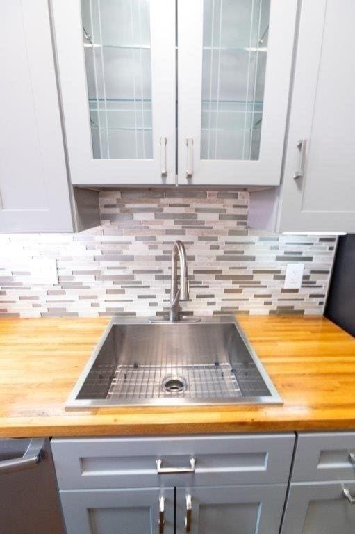 room details featuring wood counters, white cabinetry, sink, and decorative backsplash