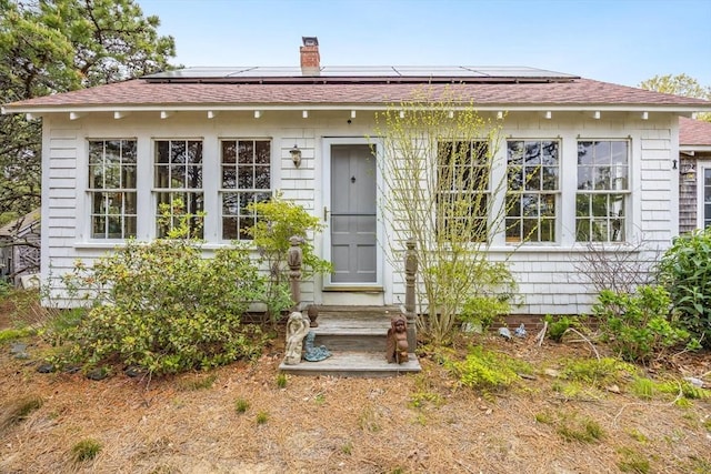 50 Higgins Ln, Wellfleet, MA 02667 - view of front of home featuring solar panels, entry steps, a shingled roof, and a chimney