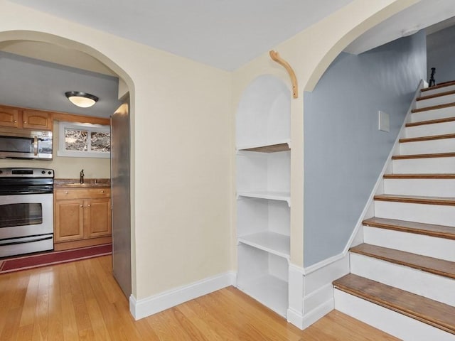 interior space featuring baseboards, arched walkways, and wood finished floors