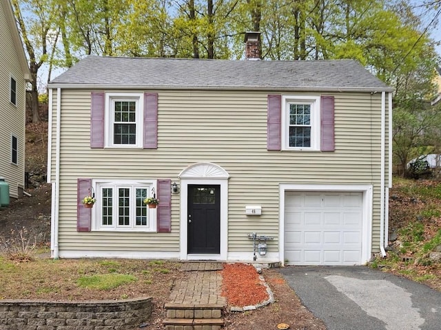 view of front of property featuring a garage, aphalt driveway, and a chimney