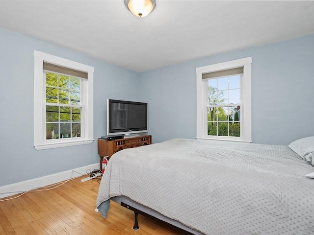 bedroom with baseboards, multiple windows, and hardwood / wood-style flooring