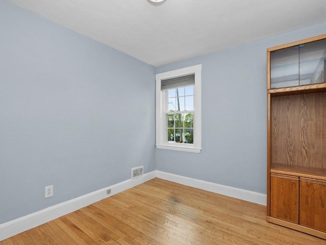 unfurnished bedroom featuring baseboards, light wood finished floors, and visible vents