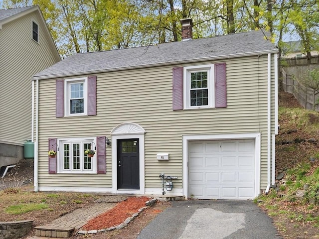 view of front of property featuring an attached garage, aphalt driveway, and a chimney
