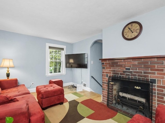living room featuring baseboards, a fireplace, wood finished floors, and visible vents