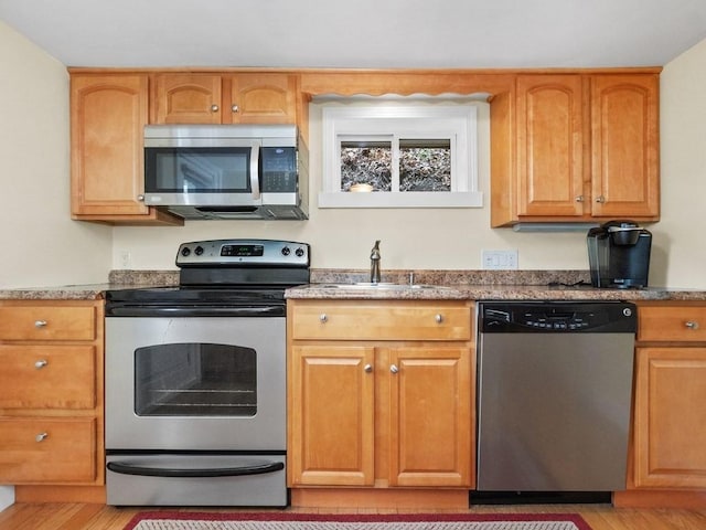 kitchen featuring appliances with stainless steel finishes, a sink, and light wood-style flooring