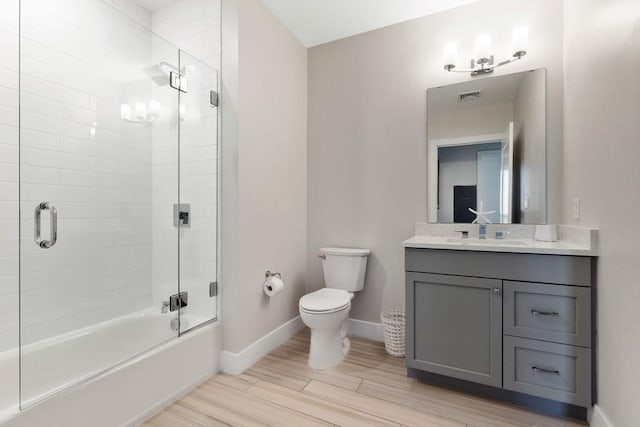 full bathroom with vanity, hardwood / wood-style floors, toilet, and combined bath / shower with glass door