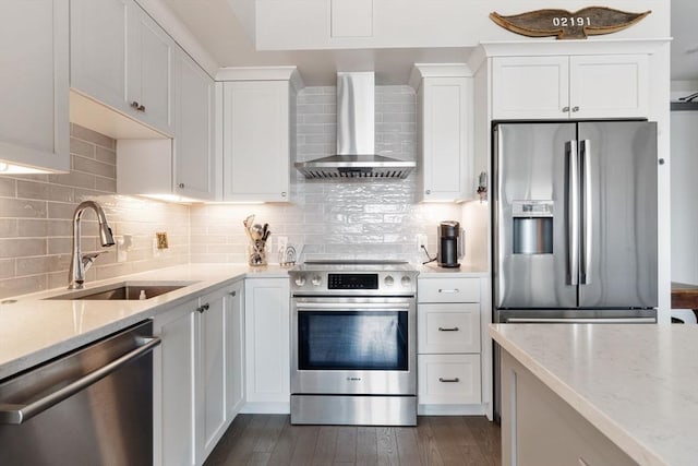 kitchen with white cabinetry, sink, light stone counters, stainless steel appliances, and wall chimney exhaust hood