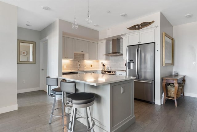 kitchen featuring decorative light fixtures, white cabinets, a center island, stainless steel refrigerator with ice dispenser, and wall chimney exhaust hood