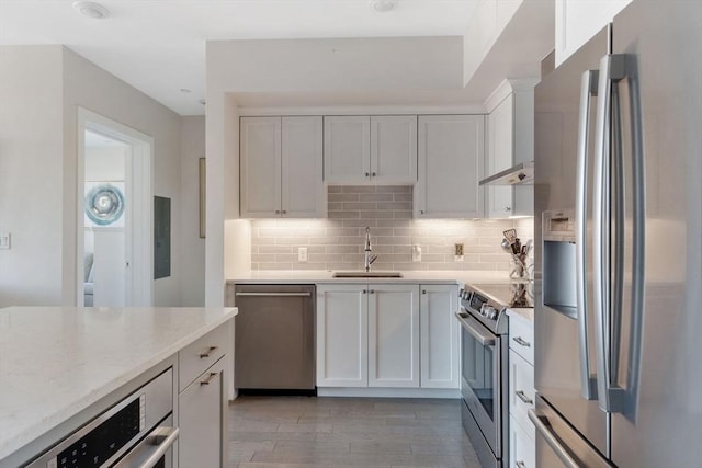 kitchen featuring white cabinetry, sink, decorative backsplash, stainless steel appliances, and light hardwood / wood-style flooring