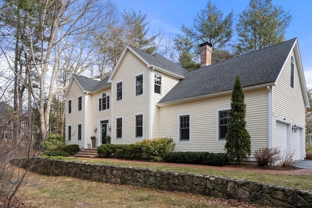 view of front of house with a shingled roof, driveway, and a chimney