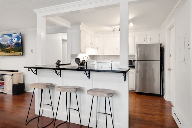 kitchen with appliances with stainless steel finishes, kitchen peninsula, white cabinetry, and a kitchen breakfast bar