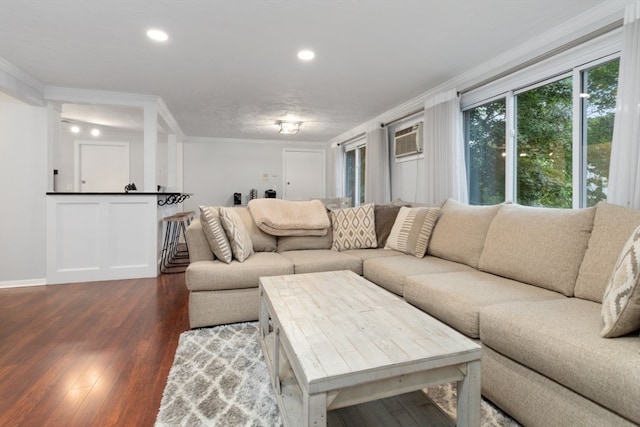 living room with dark hardwood / wood-style floors, a wall unit AC, and ornamental molding