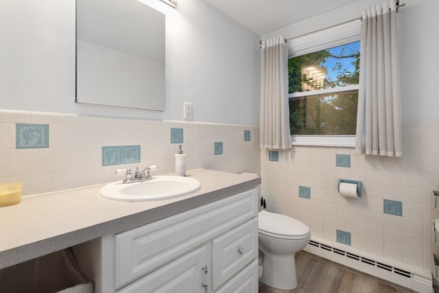 bathroom with a baseboard heating unit, toilet, tile walls, hardwood / wood-style flooring, and vanity