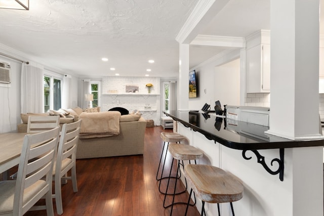 kitchen with decorative backsplash, dark hardwood / wood-style flooring, a fireplace, ornamental molding, and white cabinets